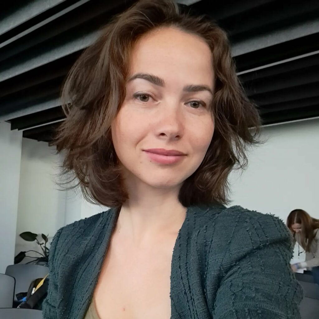 Sievil Abiieva - Prezes oraz Dyrektor ds. rozwoju, młoda kobieta o przyjaznej twarzy spogląda w dół, w stronę obiektywu aparatu