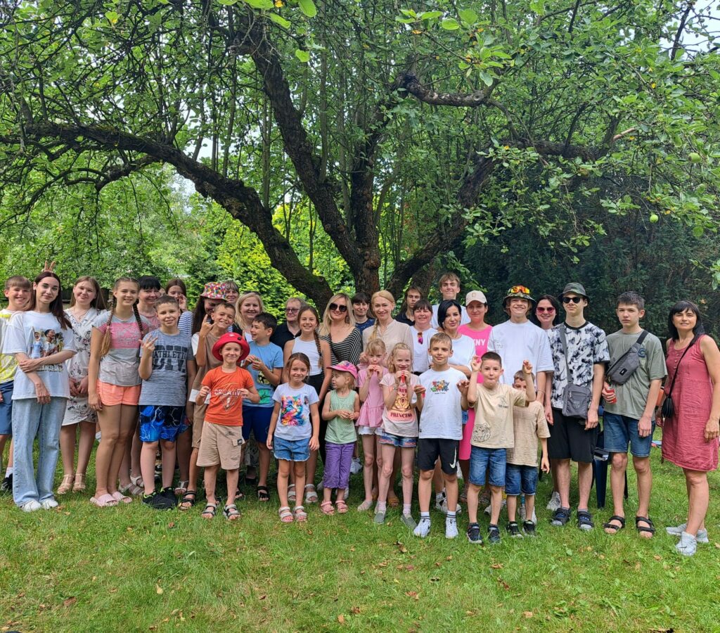 członkowie i podopieczni w grupie na zielonej trawie na tle drzewa