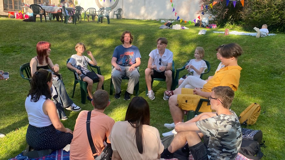 festiwal idei - młodzi ludzie siedzą w okręgu na zielonej trawie