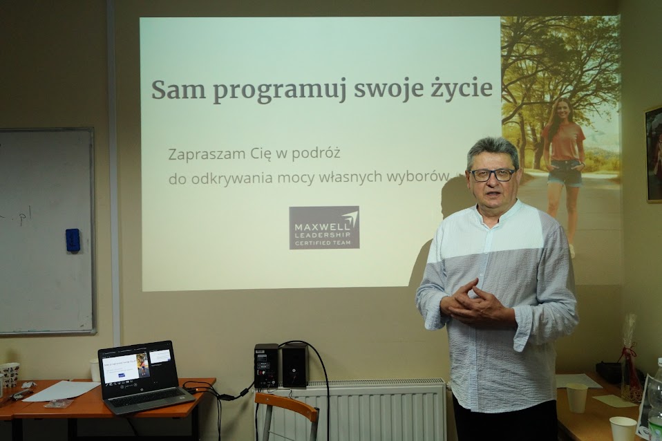 warsztaty rozwoju osobistego - mężczyzna częściowo oświetlony przez obraz z projektora prowadzi warsztaty pt. "Sam programuj swoje życie"