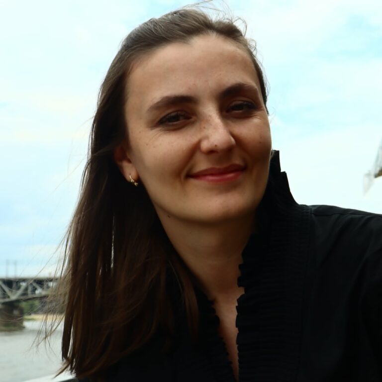 Zdjęcie przedstawia młodą, delikatnie uśmiechniętą brunetkę